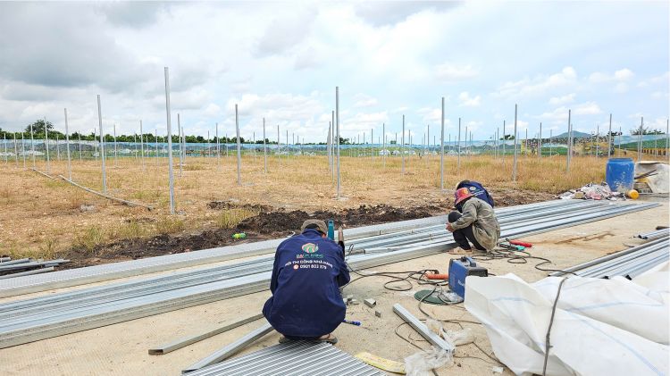 Công nhân đang thực hiện cắt sắt để thi công hệ thống khung nhà lưới trồng chanh dây.